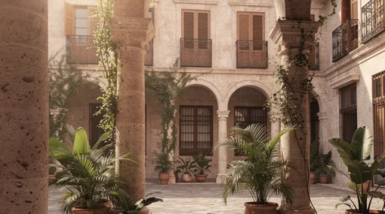 Vue panoramique d'un patio colonial restauré avec arches en pierre corail et végétation tropicale baignant dans la lumière dorée du matin