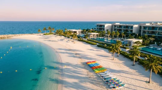 Vue aérienne d'un complexe hôtelier en bord de mer avec zone dédiée aux sports nautiques et équipements colorés