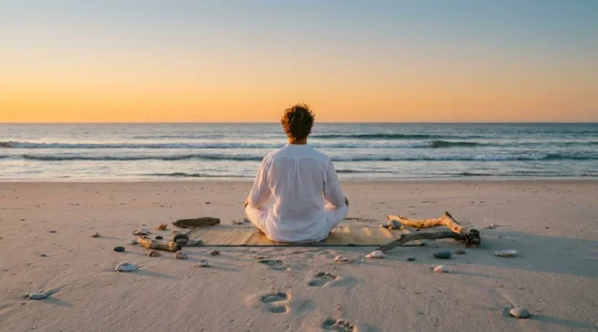 Personne en méditation sur une plage de sable fin au coucher du soleil pour illustrer la décompression mentale en séjour balnéaire